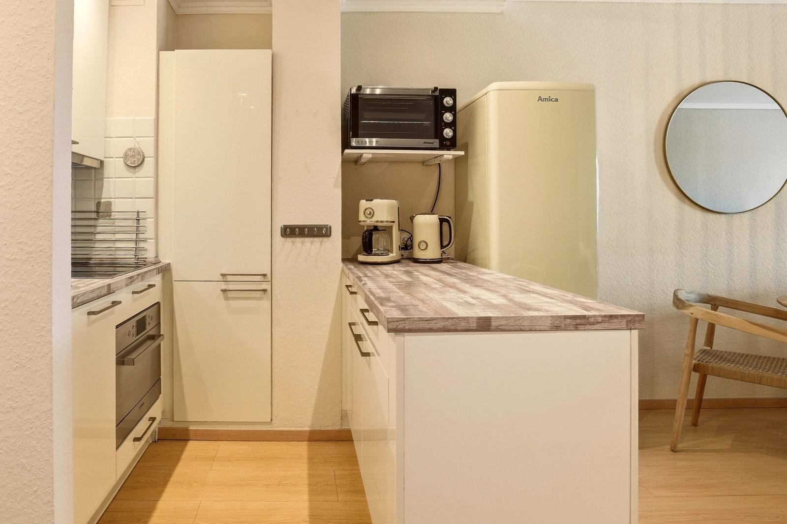 Küche mit Arbeitsplatte, Kühlschrank, Toaster und Kaffeemaschine.