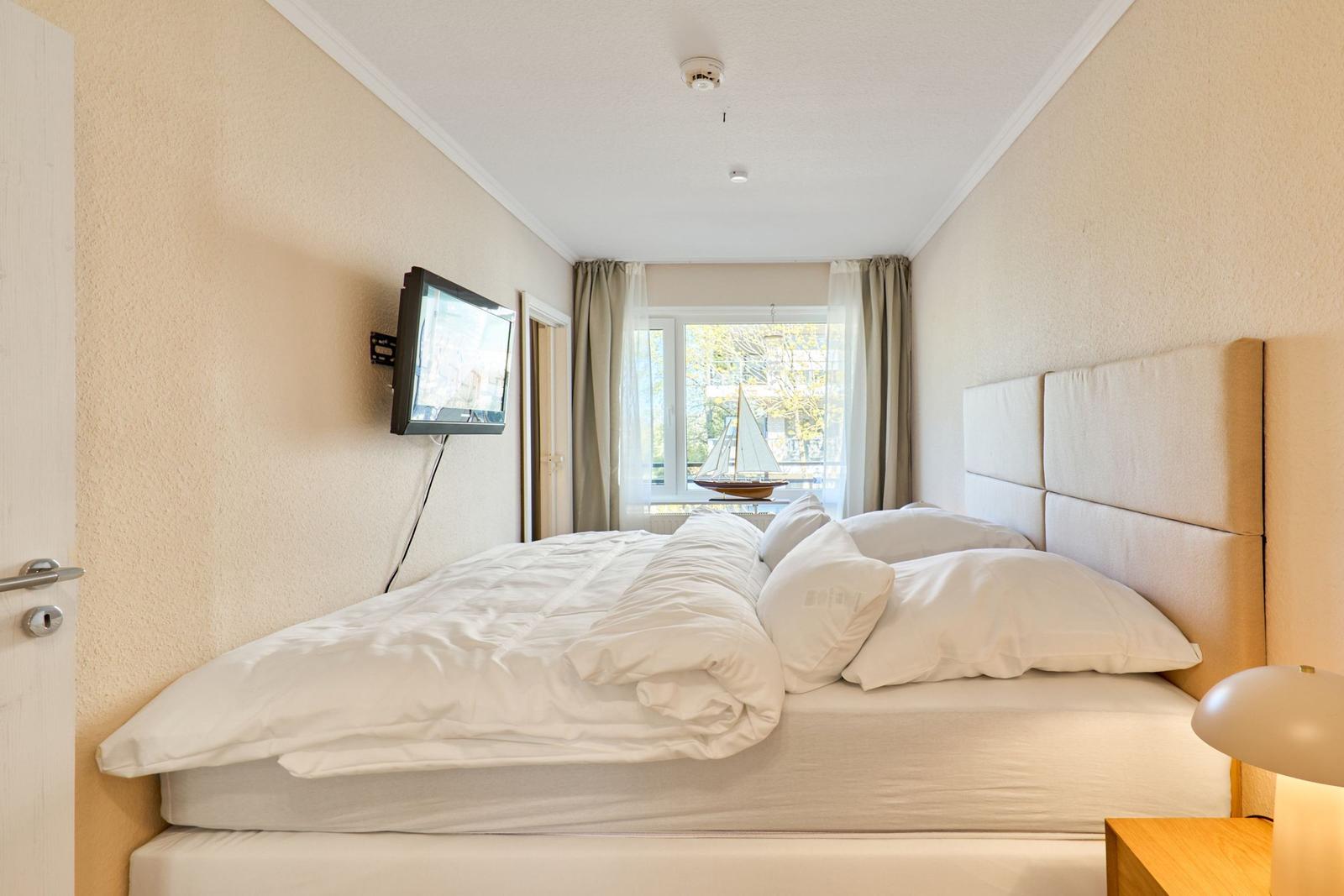 Schlafzimmer mit Bett, Fernseher und Fenster mit Blick.