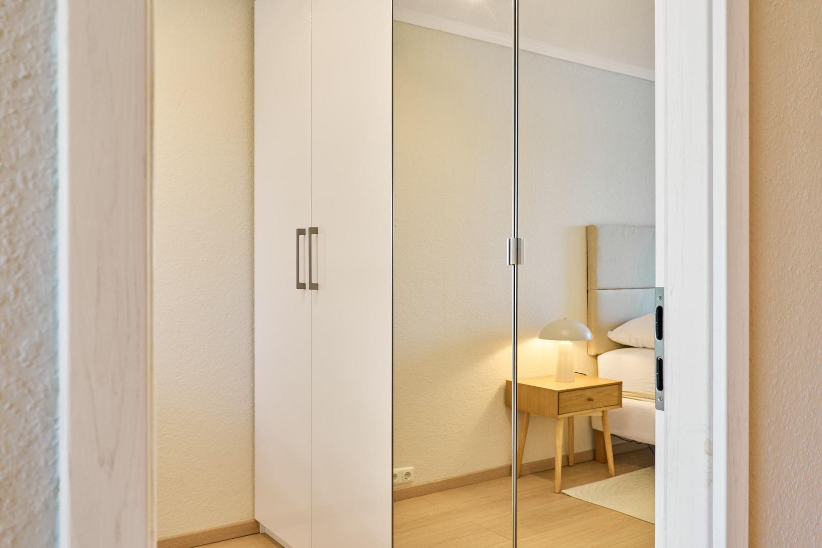 Schlafzimmer mit Spiegelschrank, Nachttisch und Bett