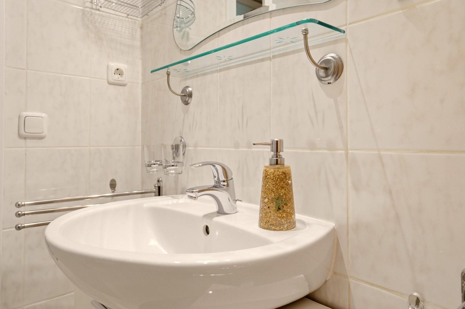 Badezimmer mit Waschbecken, Spiegel und Seifenspender.
