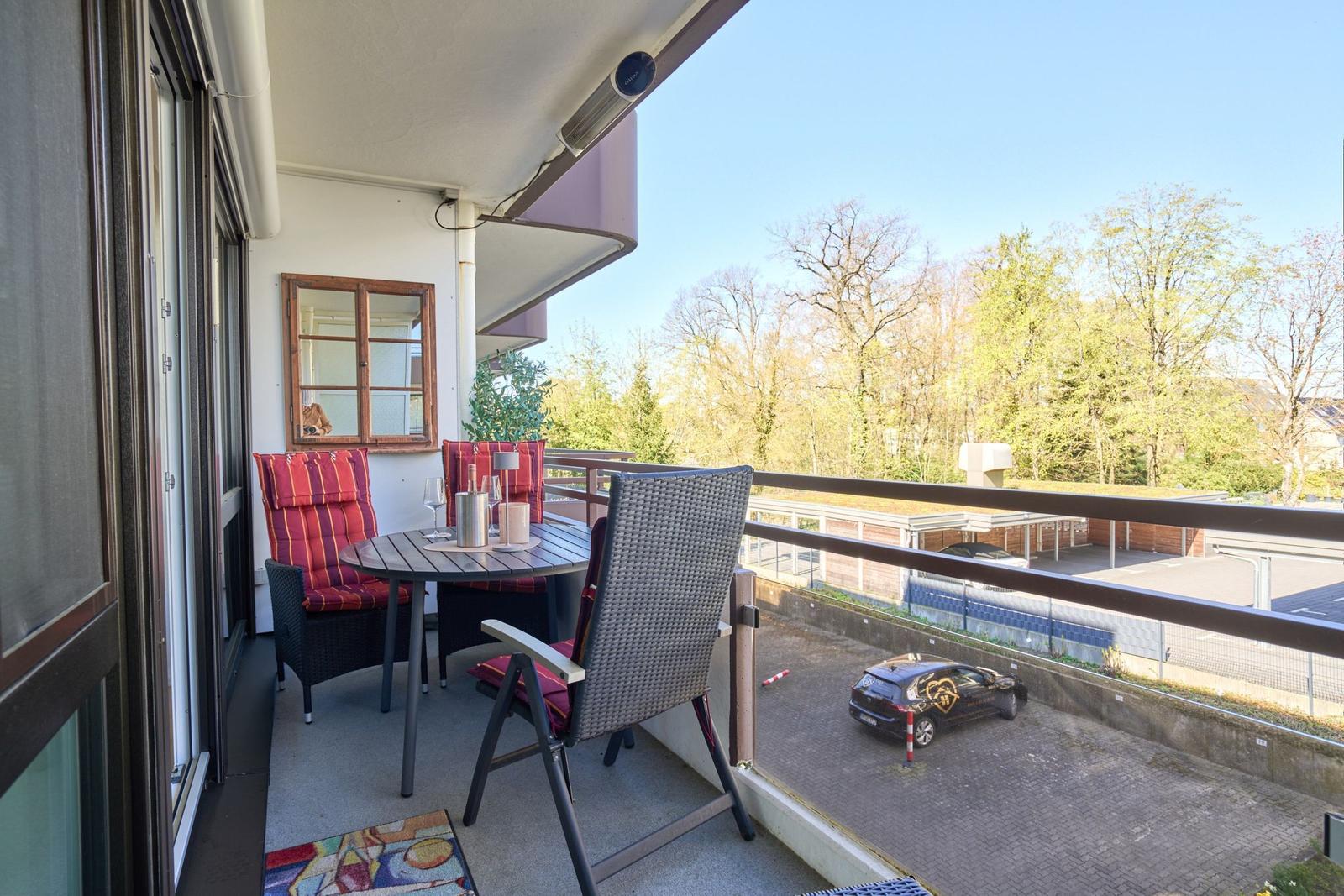 Terrasse mit Tisch, Stühlen und Blick auf Bäume.