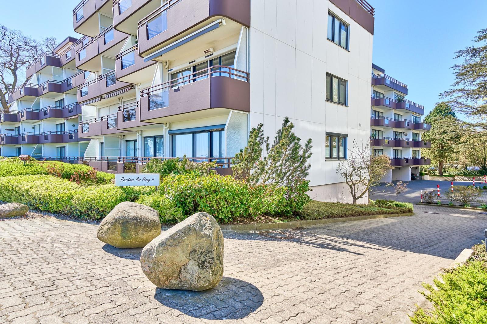 Modernes Mehrfamilienhaus mit Balkonen und gepflegtem Gartenbereich.