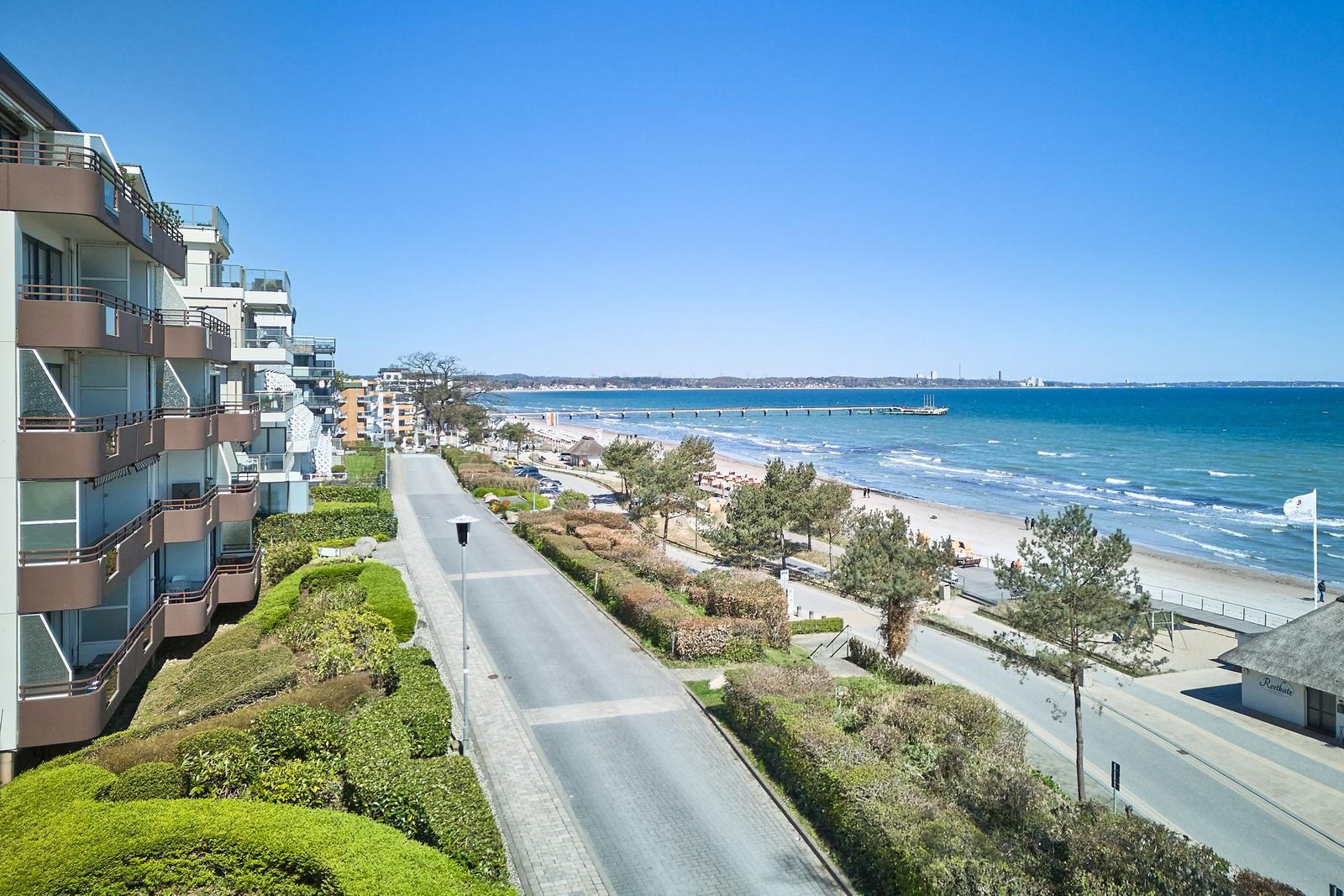 Strandpromenade mit Meerblick, modernen Gebäuden und gepflegten Grünflächen.