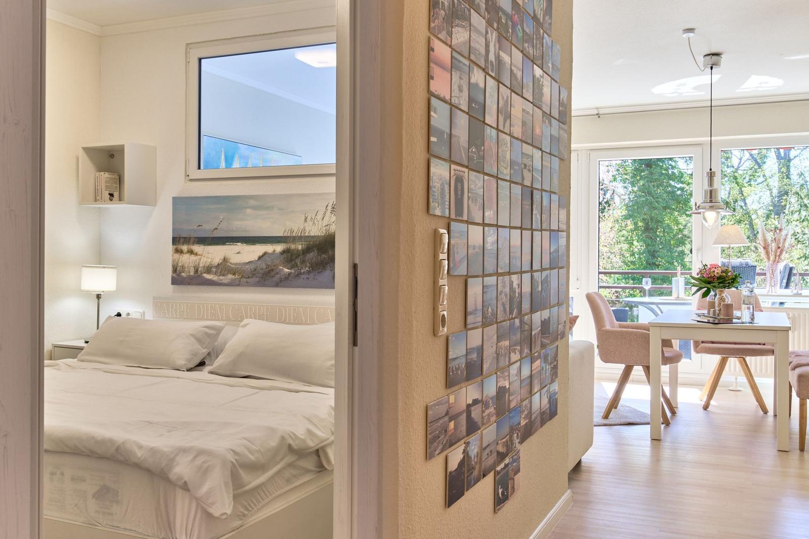 Schlafzimmer mit Bett und Wandbild. Durchgang zu Esszimmer mit Tisch und Stühlen.