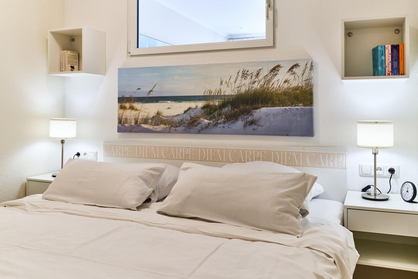 Schlafzimmer mit Bett, Nachttischen und Wandbild an der Wand.