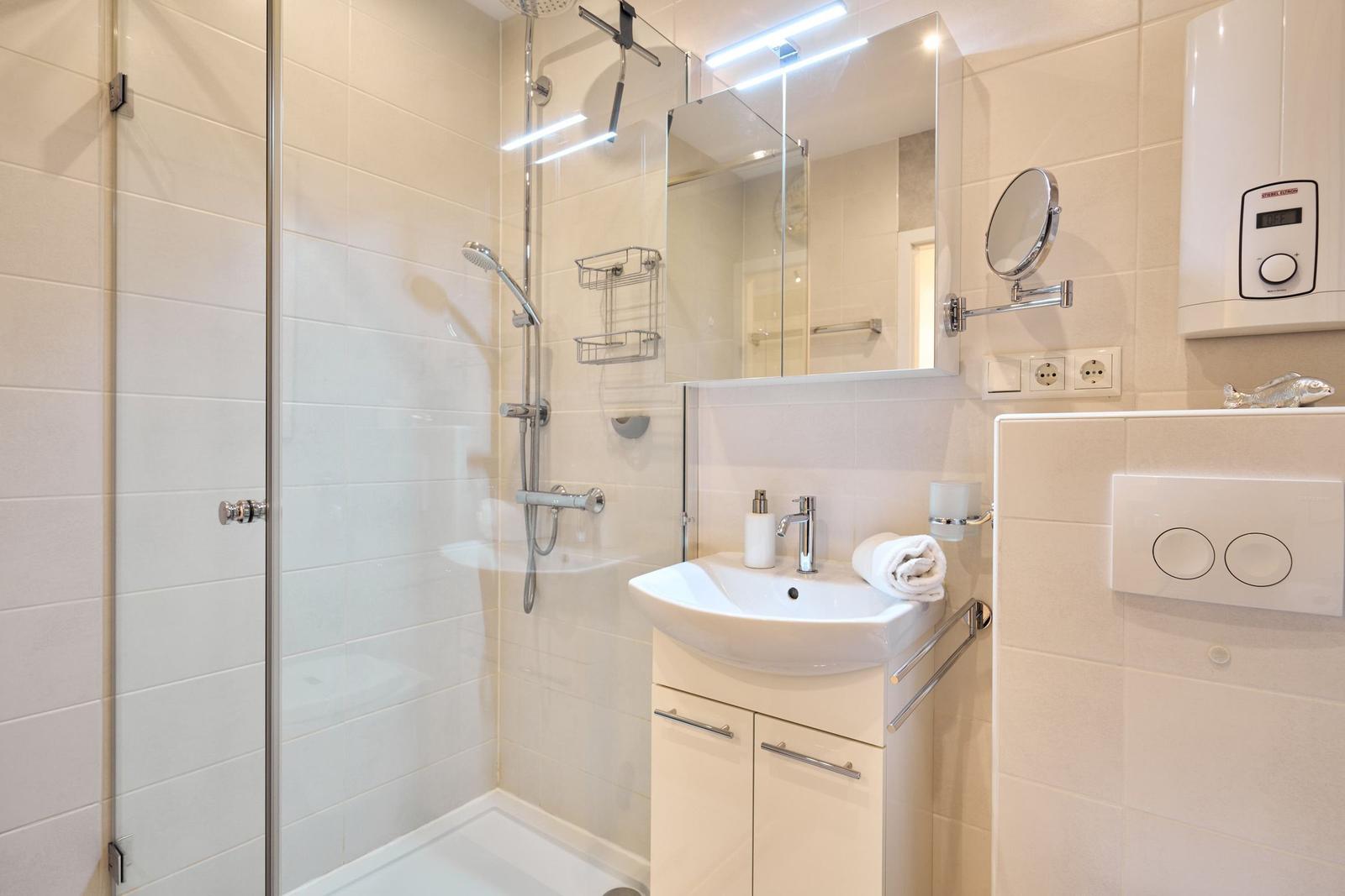 Bad mit Dusche, Waschbecken und Spiegelschrank.