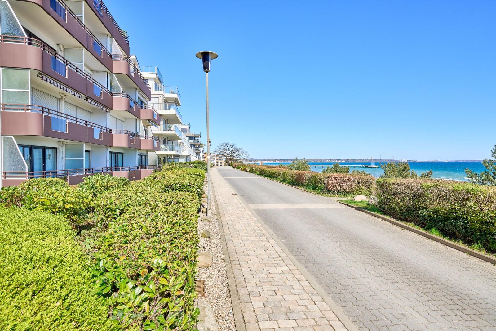 Strandpromenade mit Wohnhäusern und Blick auf das Meer.