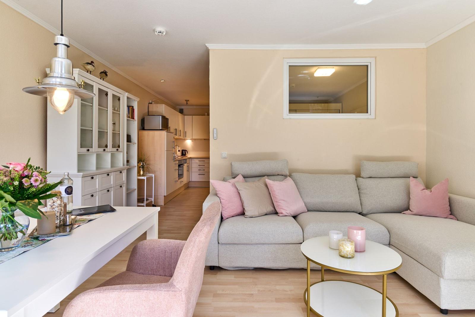 Wohnzimmer mit Sofa, Couchtisch und Blick in die Küche.