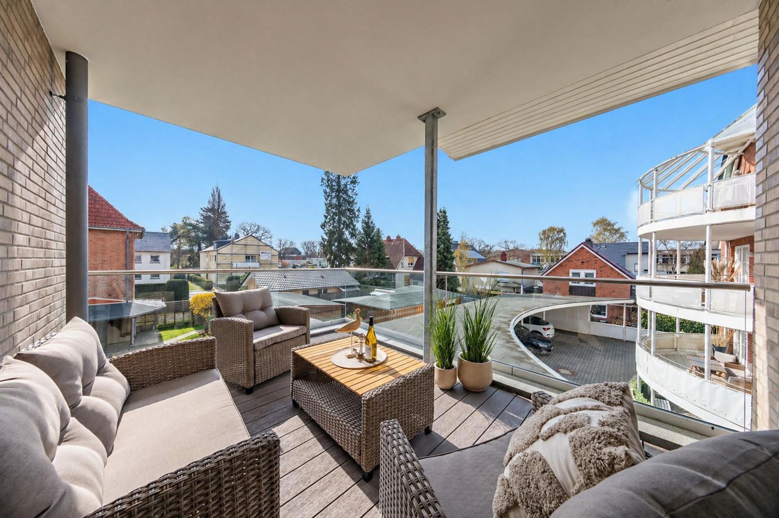 Terrasse mit Sitzgruppe, Tisch und Pflanzen. Blick auf Wohngebiet und Parkhaus.