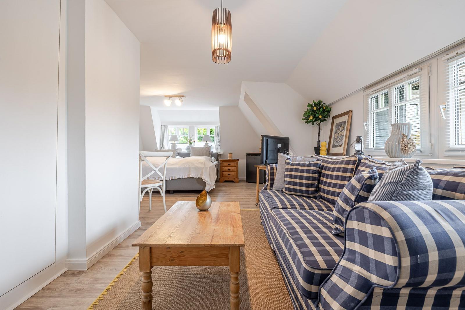 Wohnbereich mit Sofa, Couchtisch und Blick in Schlafzimmer mit Bett.