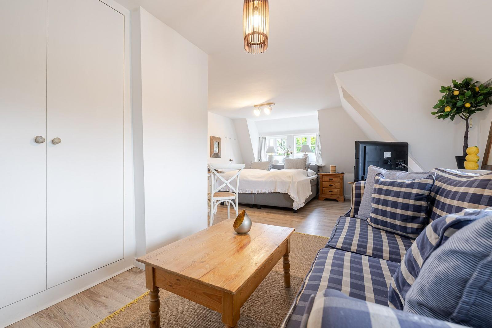 Wohnbereich mit Sofa, Couchtisch und Blick in Schlafzimmer mit Bett.