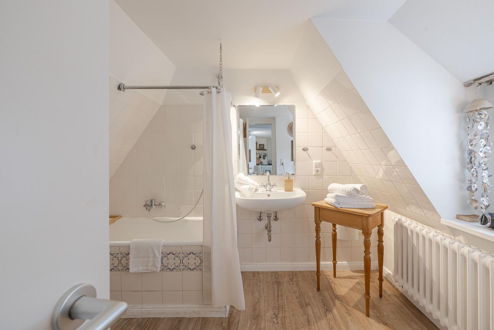 Badezimmer mit Badewanne, Waschbecken und Holztisch