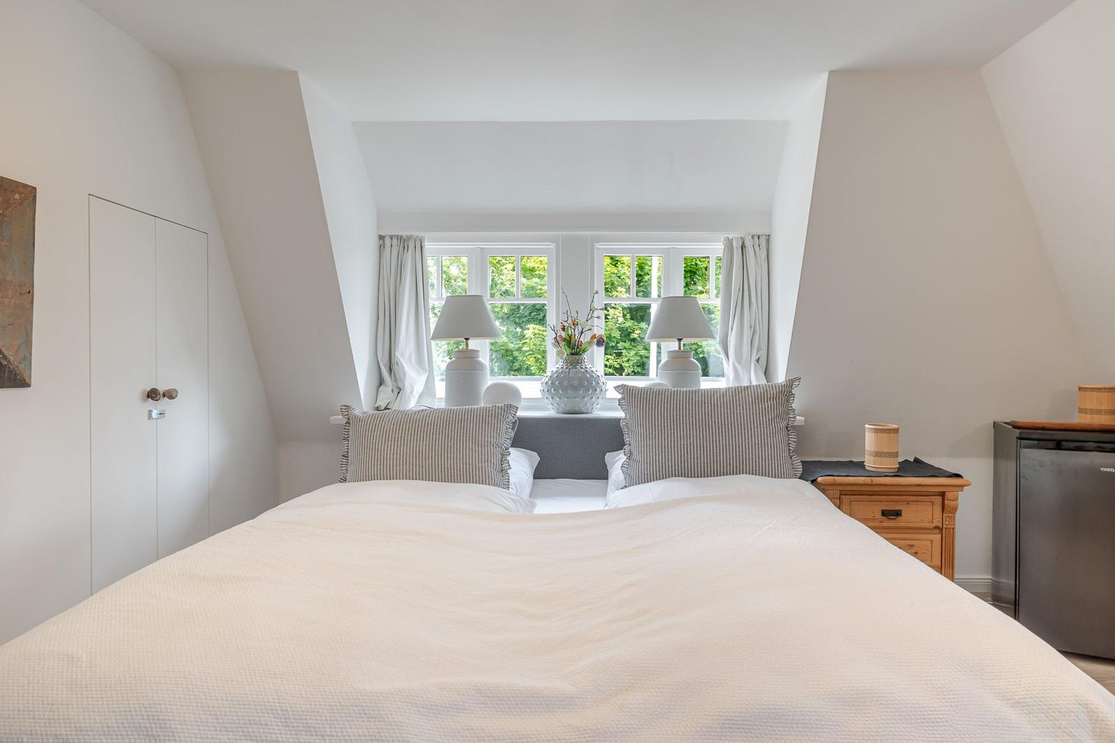 Schlafzimmer mit Doppelbett, Fenster und Nachttisch