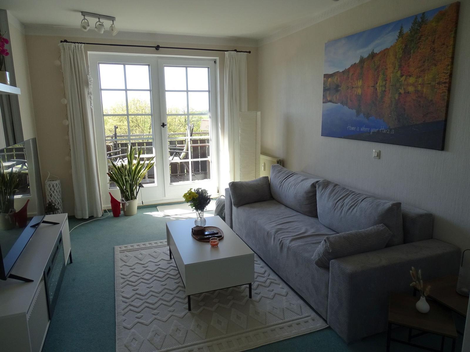Wohnzimmer mit Sofa, Couchtisch und Blick auf Balkon