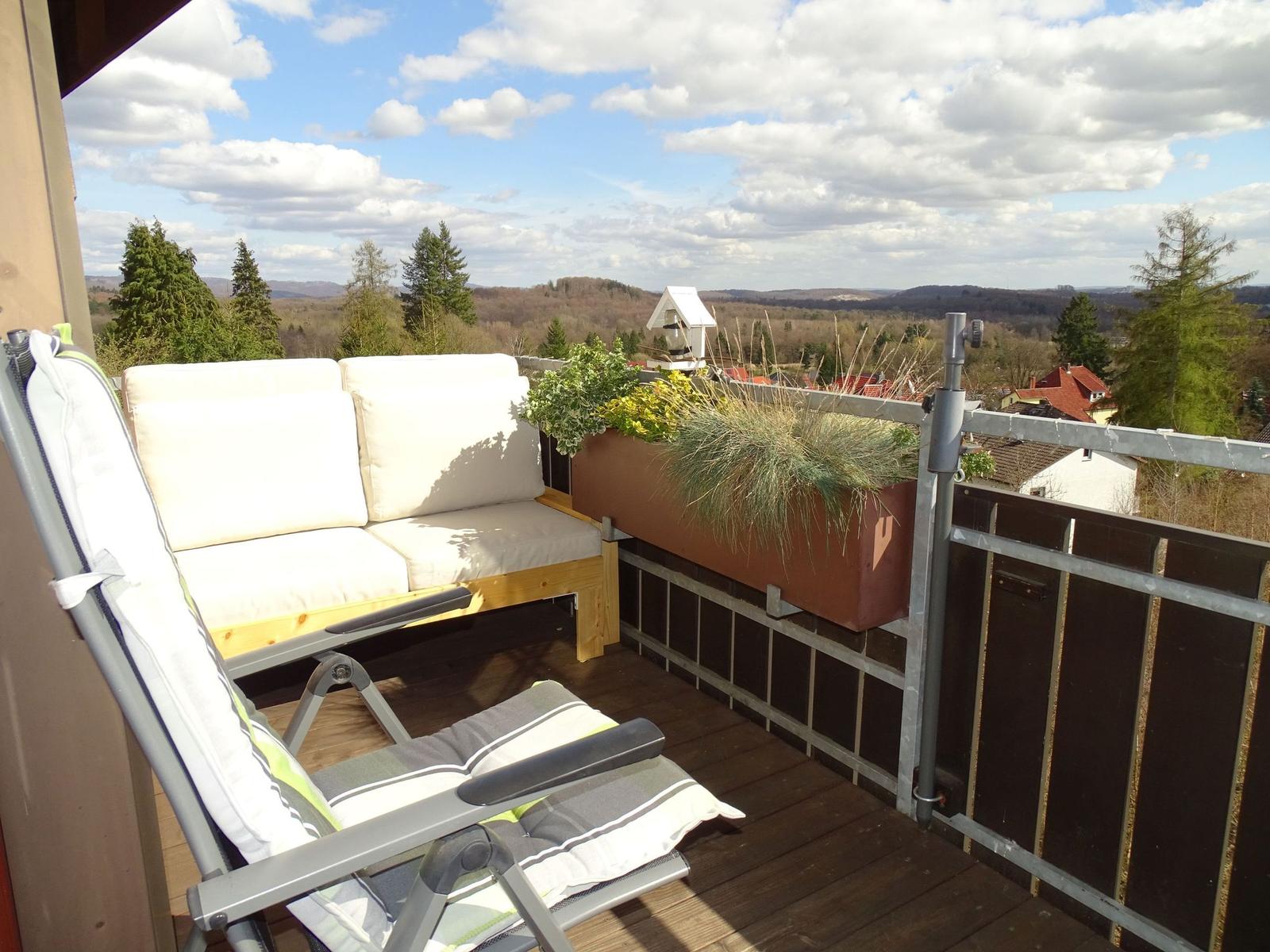 Terrasse mit Sitzmöbeln und Blick auf Wald und Hügel.