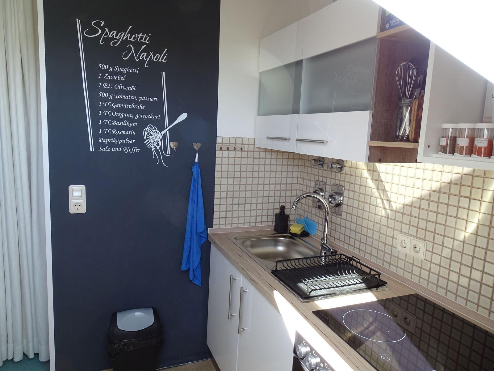 Küche mit Spüle, Herd und Wand mit Rezept.
