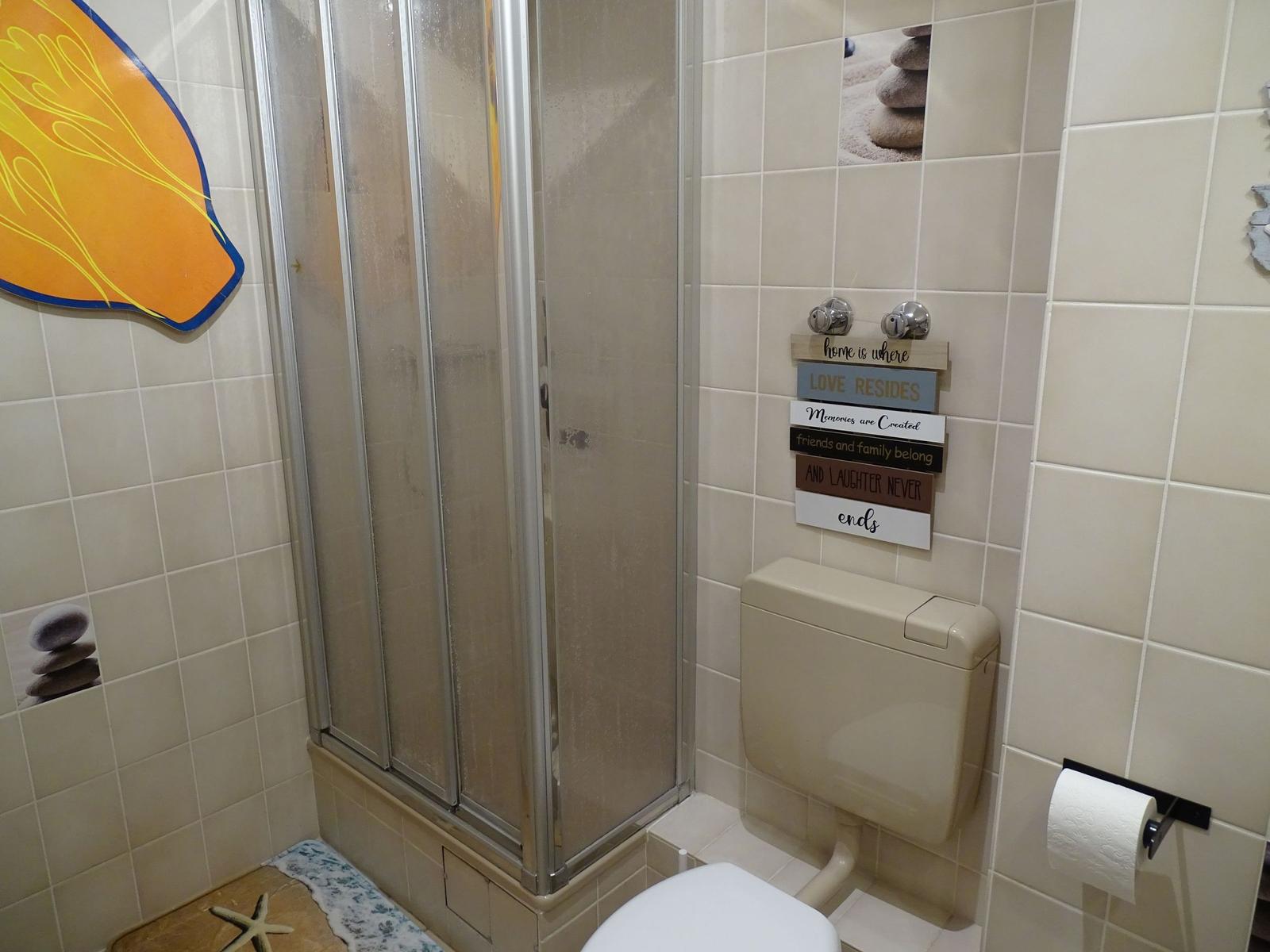 Badezimmer mit Dusche, Toilette und Wanddekoration.