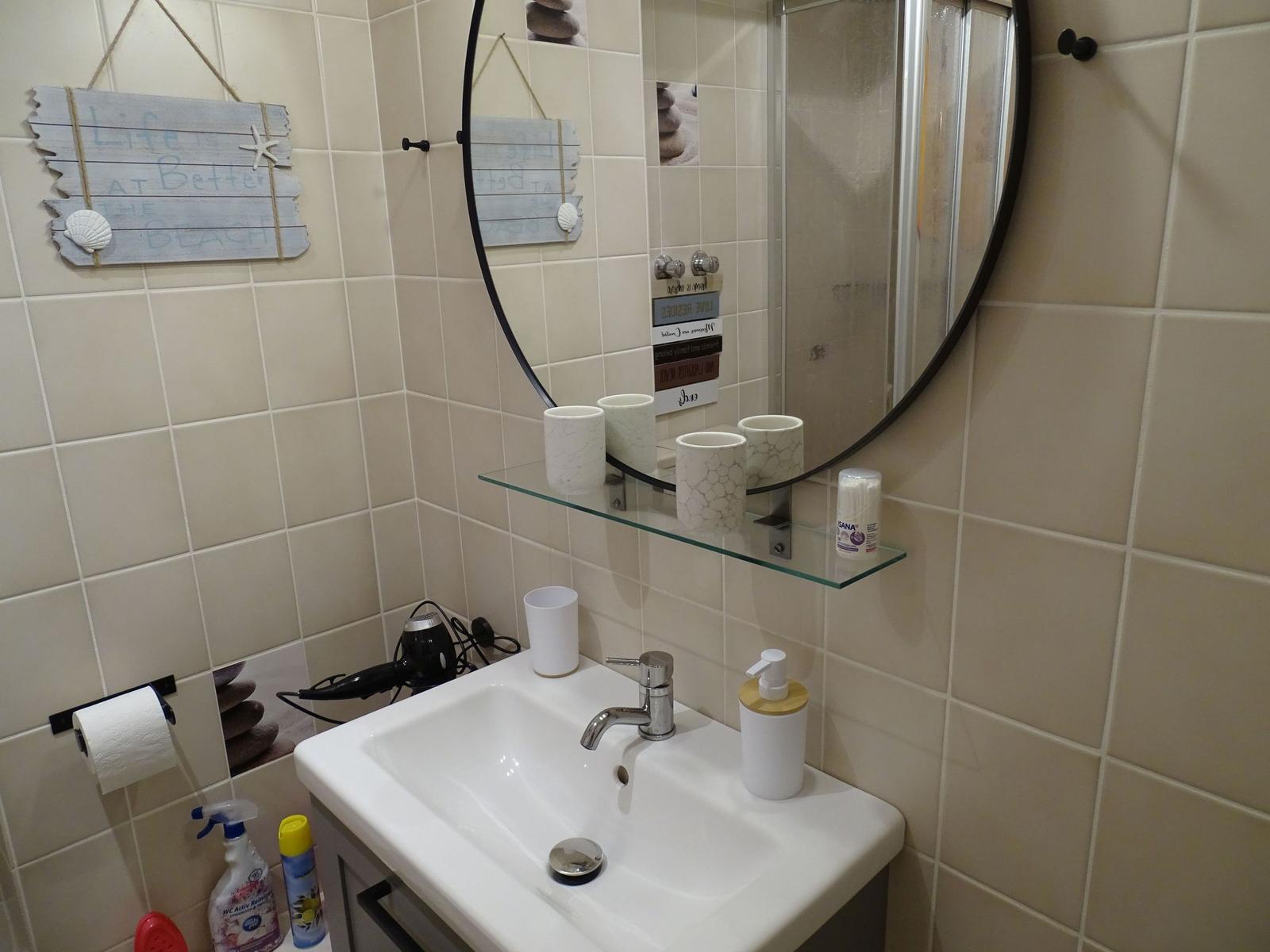 Bad mit Waschbecken, Spiegel und Handtuchhalter an der Wand.
