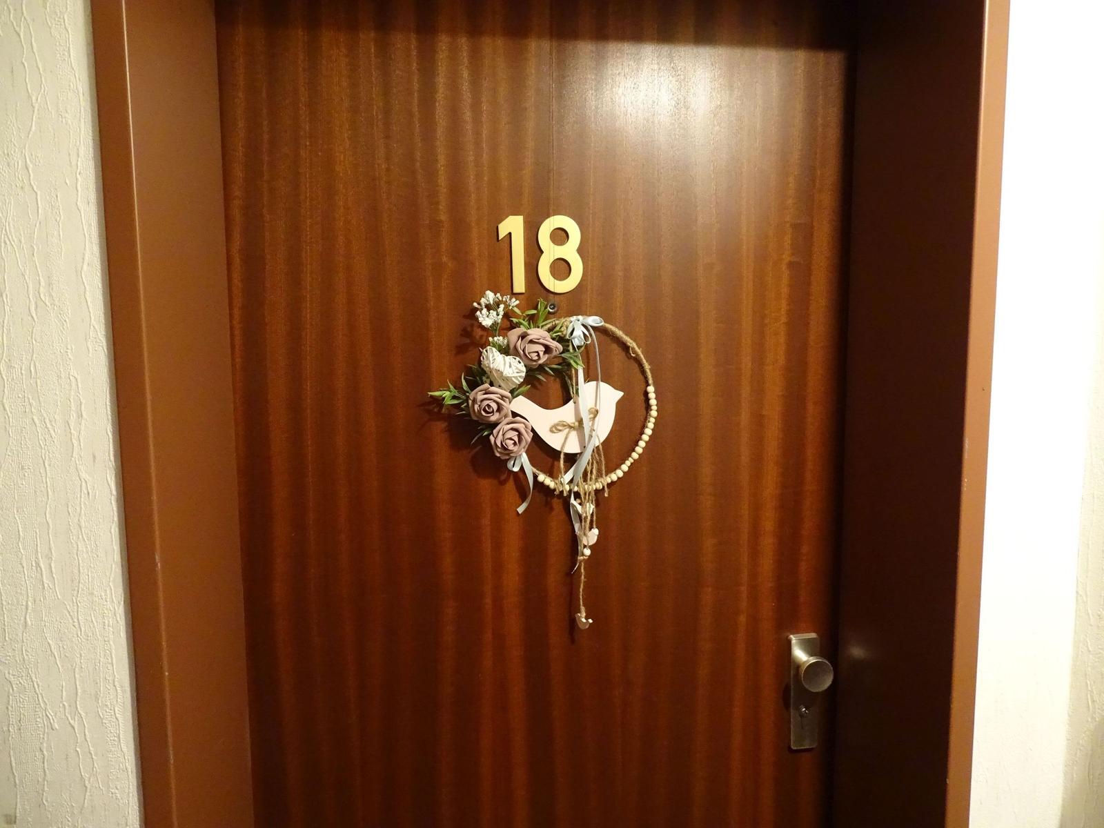 Türe mit der Nummer 18 und einem dekorativen Kranz mit Vogel.