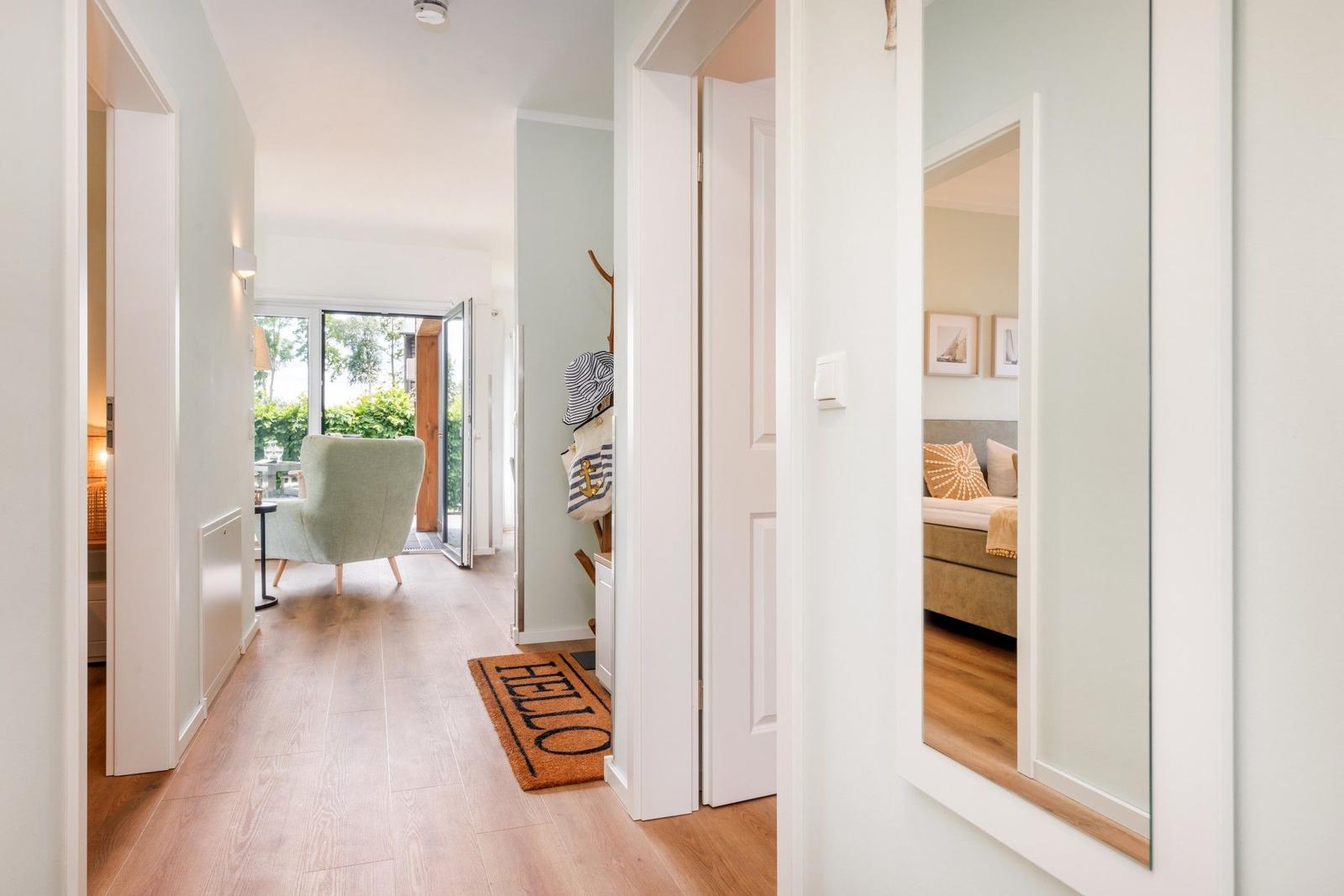 Flur mit Blick in Wohn- und Schlafzimmer. Holzfußboden und Tür zum Garten.