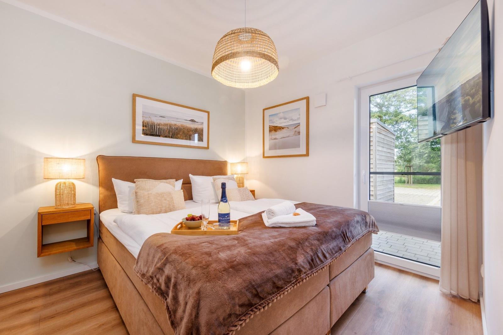 Doppelbett mit Decke, Fernseher und Blick auf Balkon.