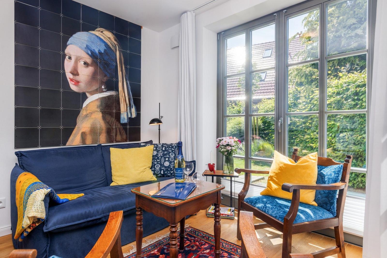 Wohnzimmer mit Sofa, Stuhl und Wandbild von Mädchen mit Perlenohrring.