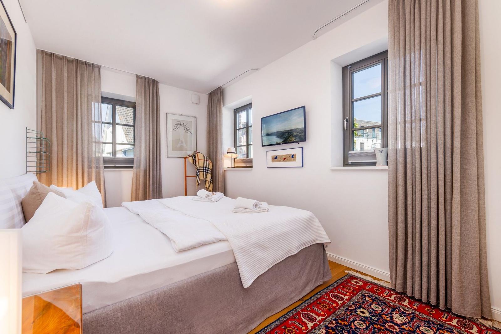 Schlafzimmer mit Bett, Fenstern und Teppich