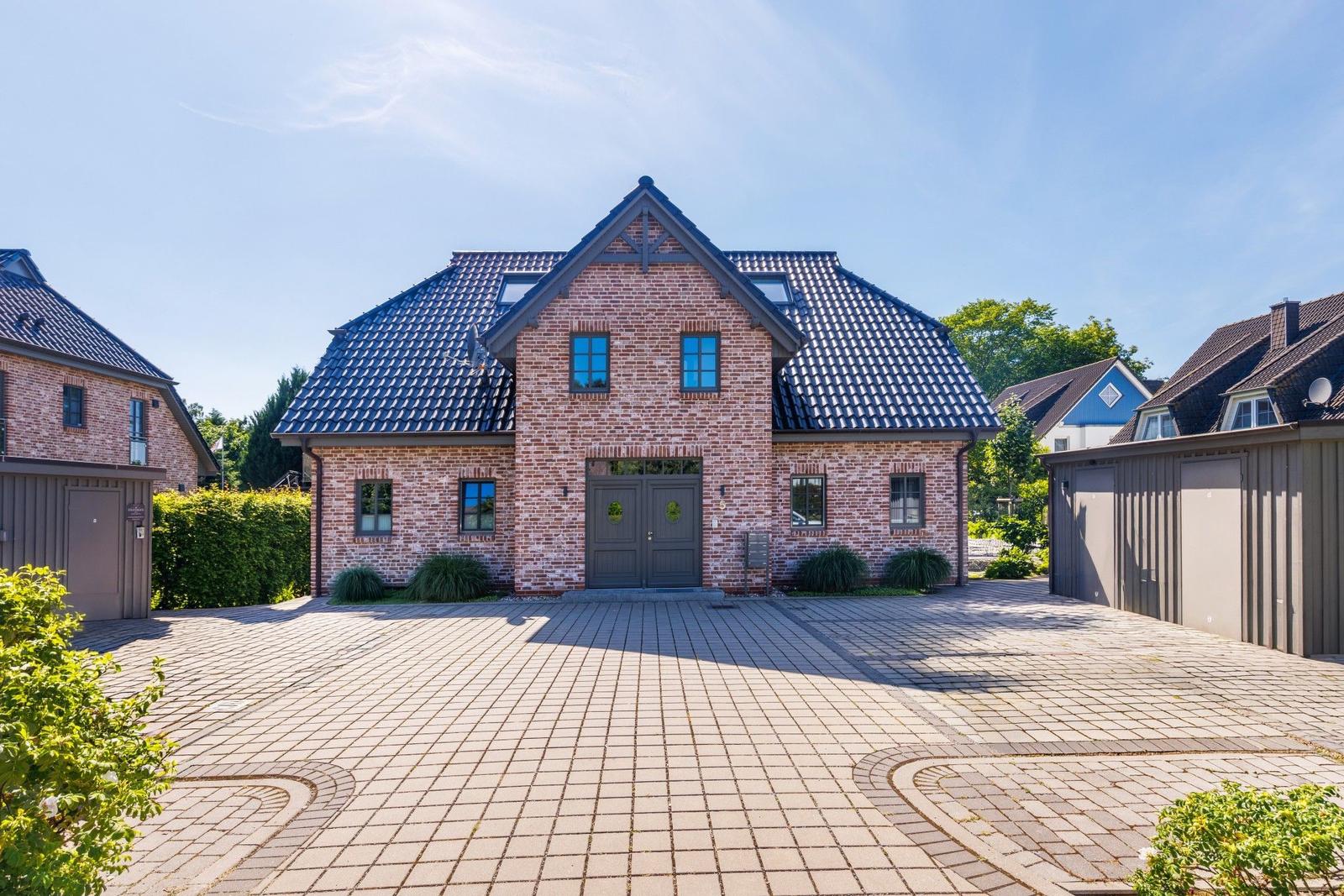 Einfamilienhaus mit Ziegelfassade und Dachgauben. Vorgarten mit gepflastertem Hof.