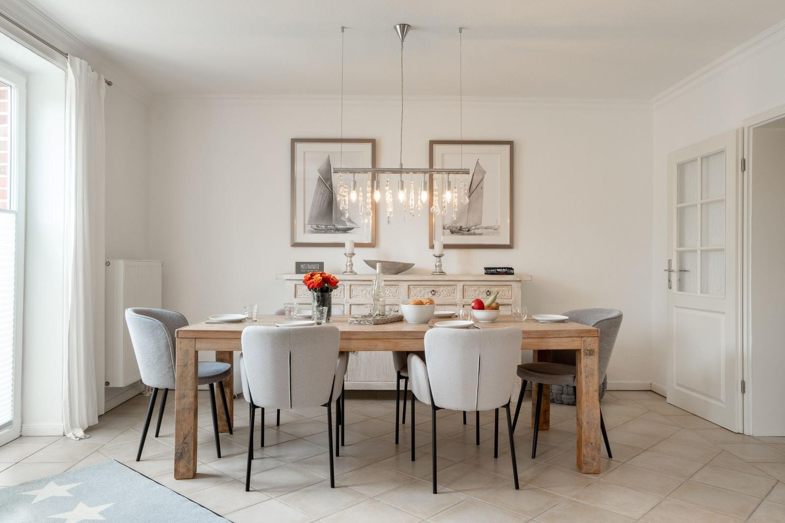 Dining room with wooden table, chairs, and wall art. Ceiling light and window visible.