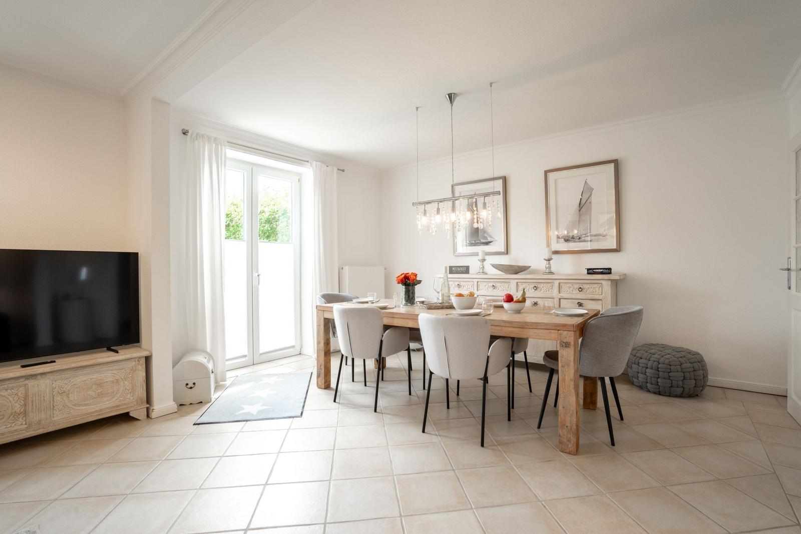 Dining room with wooden table, chairs, and window. TV on sideboard.