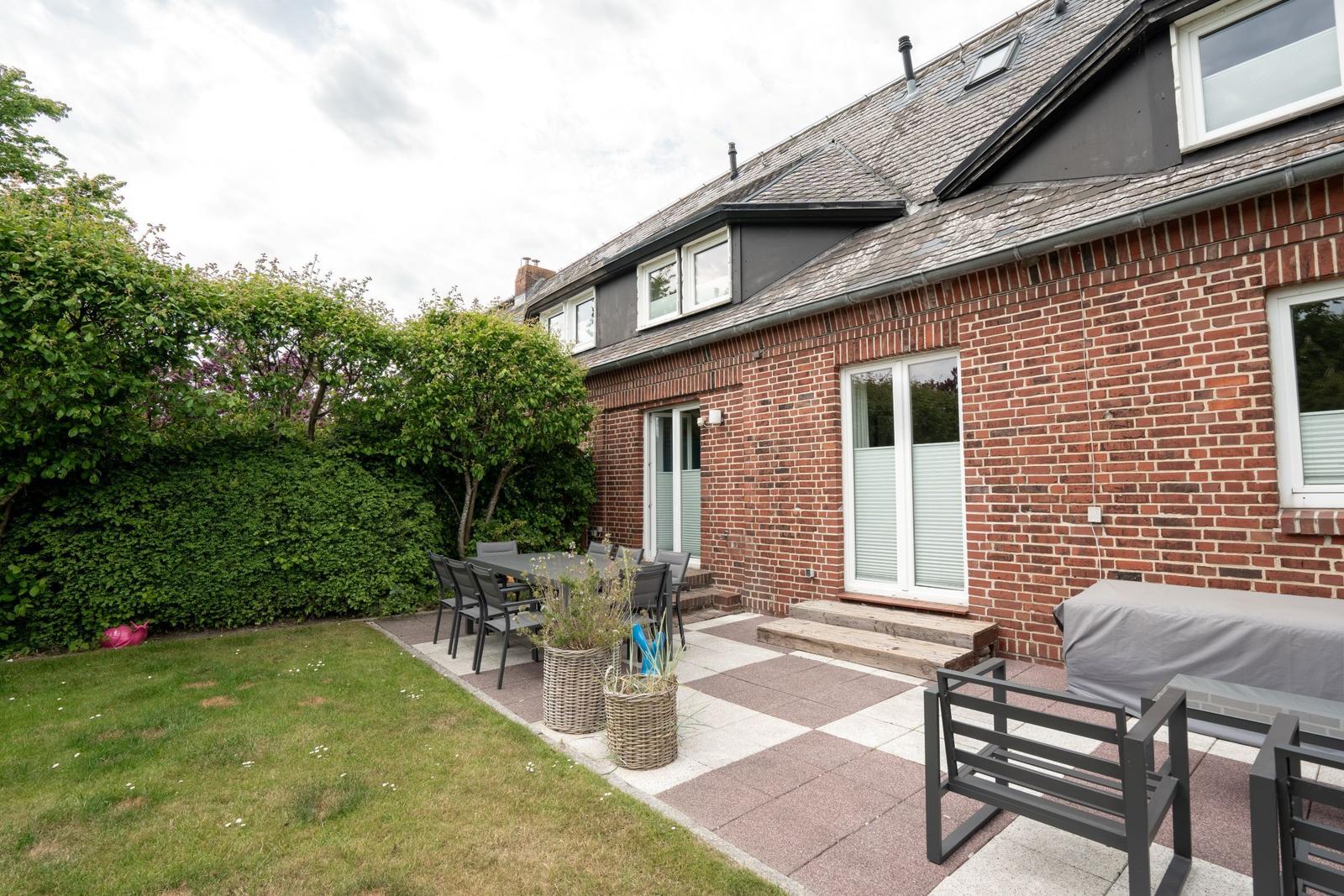 Red brick house with terrace, garden, and seating areas.