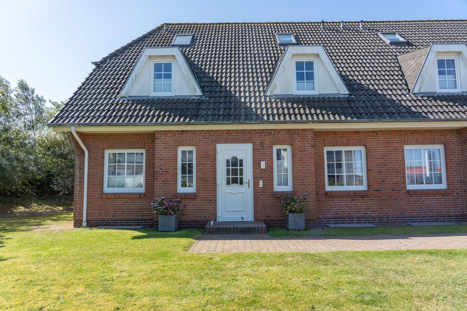 Rotes Backsteingebäude mit Dachfenstern und weißer Tür