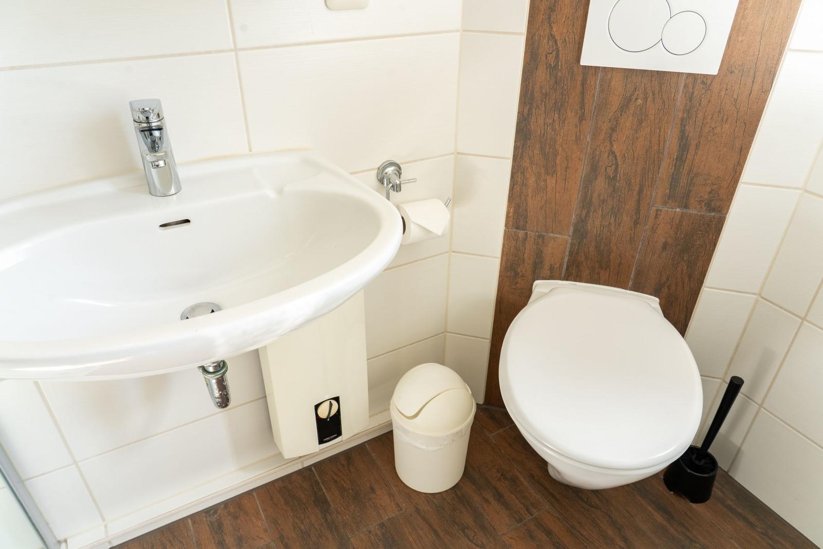 Bad mit Waschbecken, Toilette und Mülleimer