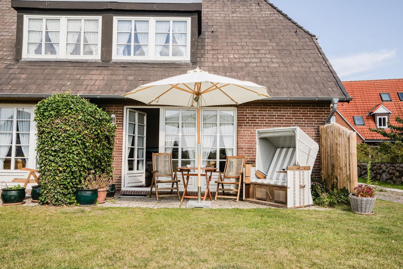 Haus mit Terrasse, Sonnenschirm, Liegestühlen und Grasfläche
