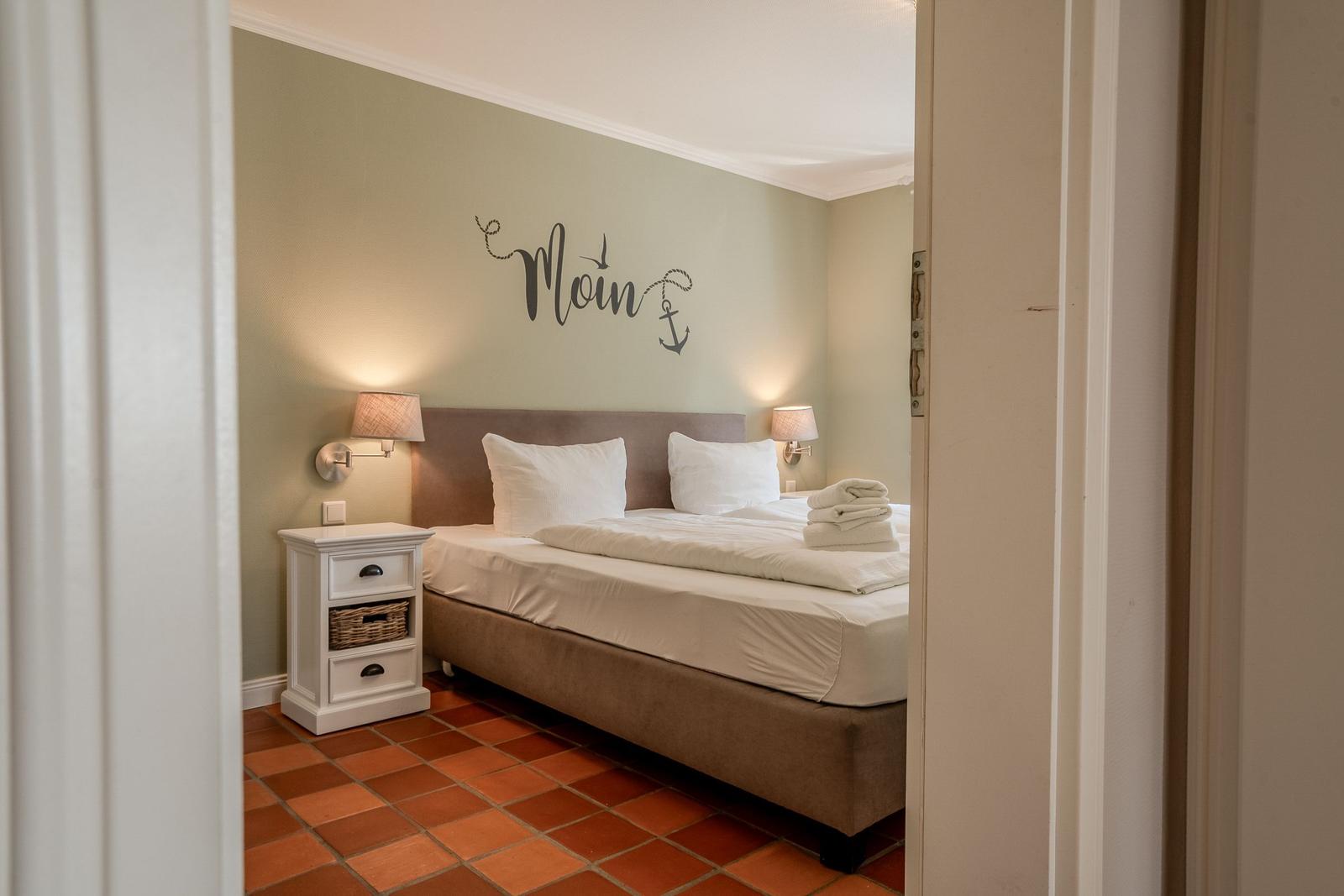 Schlafzimmer mit Bett, Nachttisch und Wanddekoration.