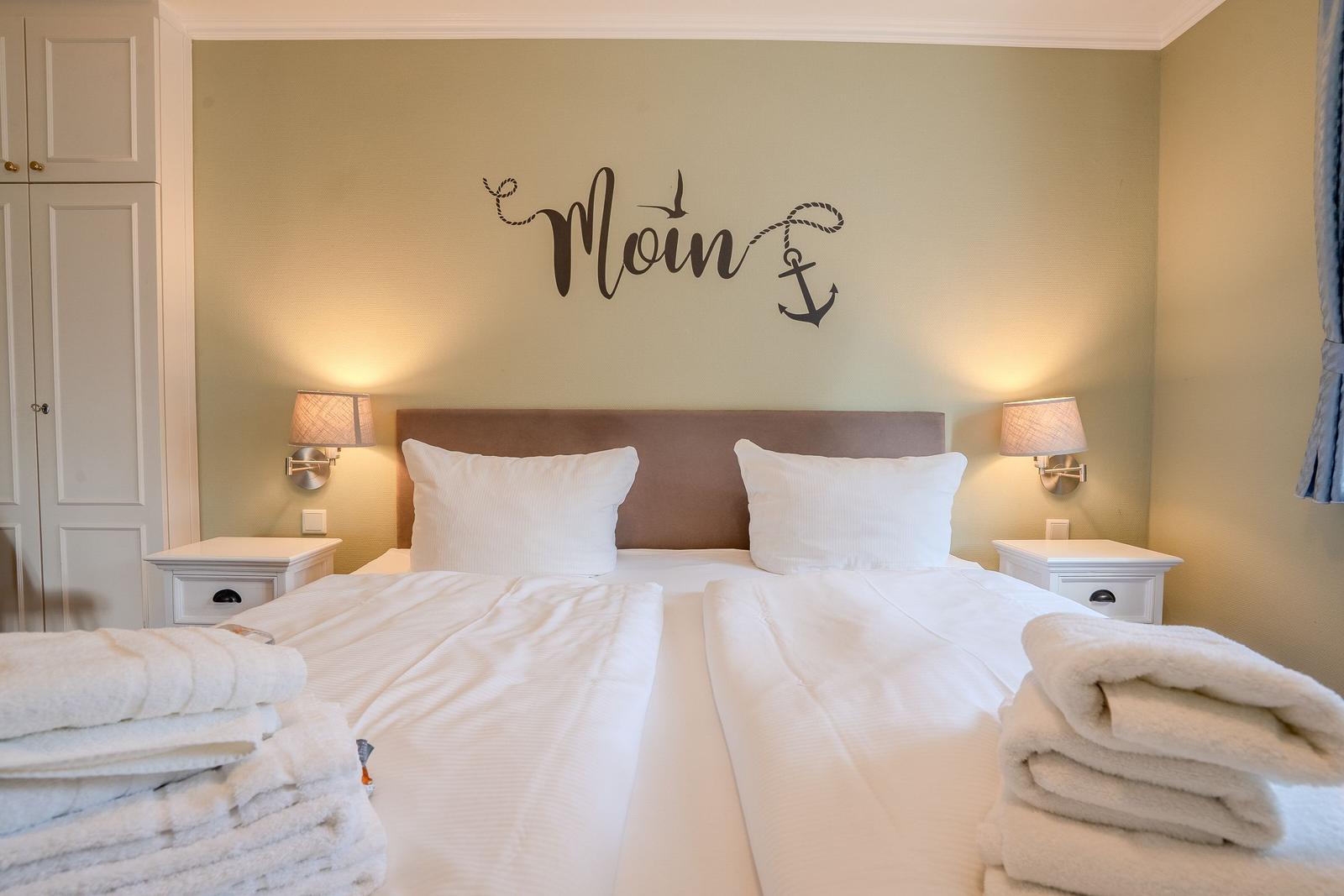 Schlafzimmer mit Doppelbett, Nachttischen und Wanddekoration mit Anker.