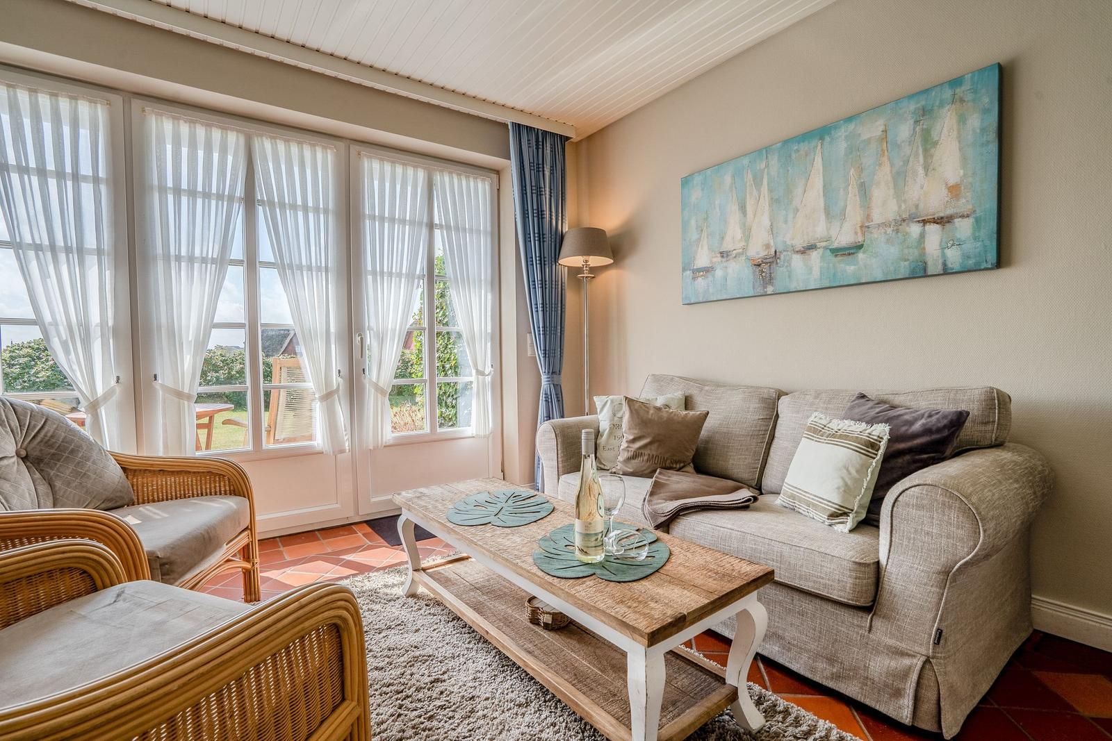 Wohnzimmer mit Sofa, Sitzgarnitur, Tisch und Wandbild mit Segelbooten.