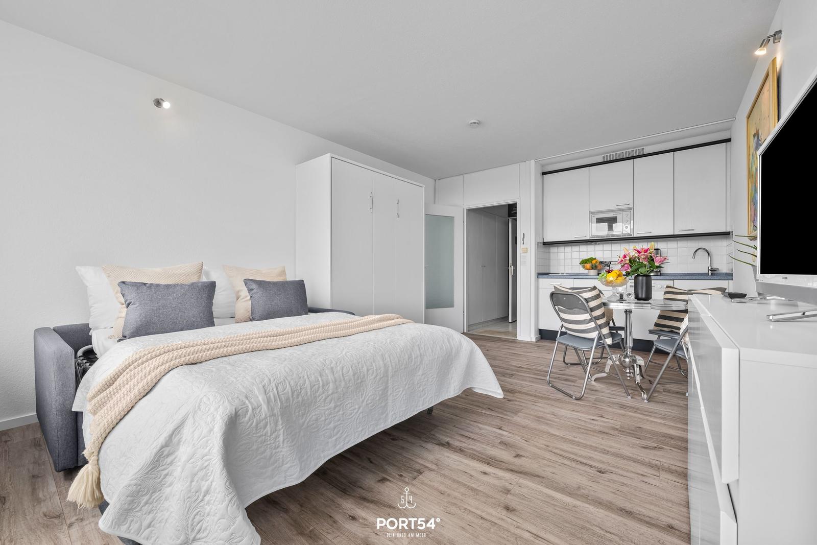 Bedroom with bed, wardrobe, and adjacent kitchen with dining table.