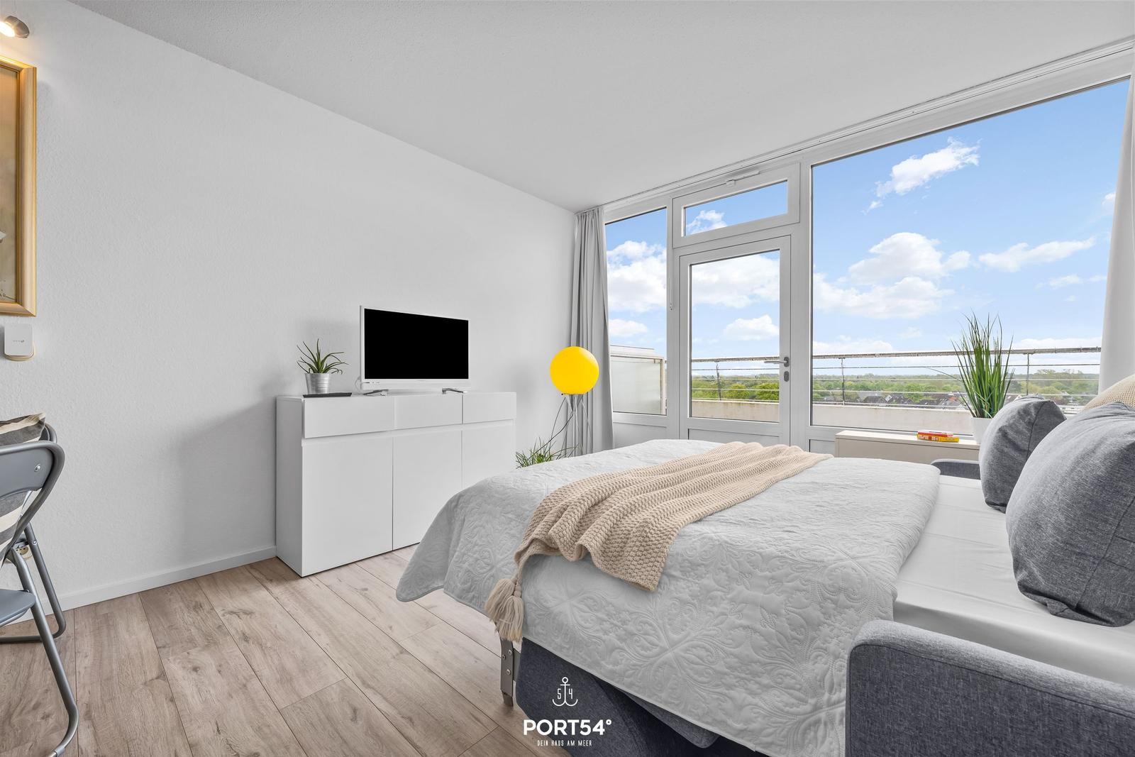 Bedroom with bed, TV, and balcony view.
