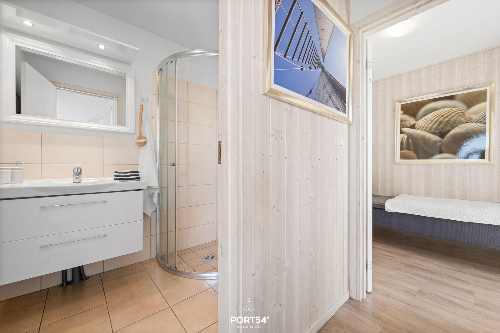 Badezimmer mit Dusche und Waschbecken. Schlafzimmer mit Bett und Wandbild.