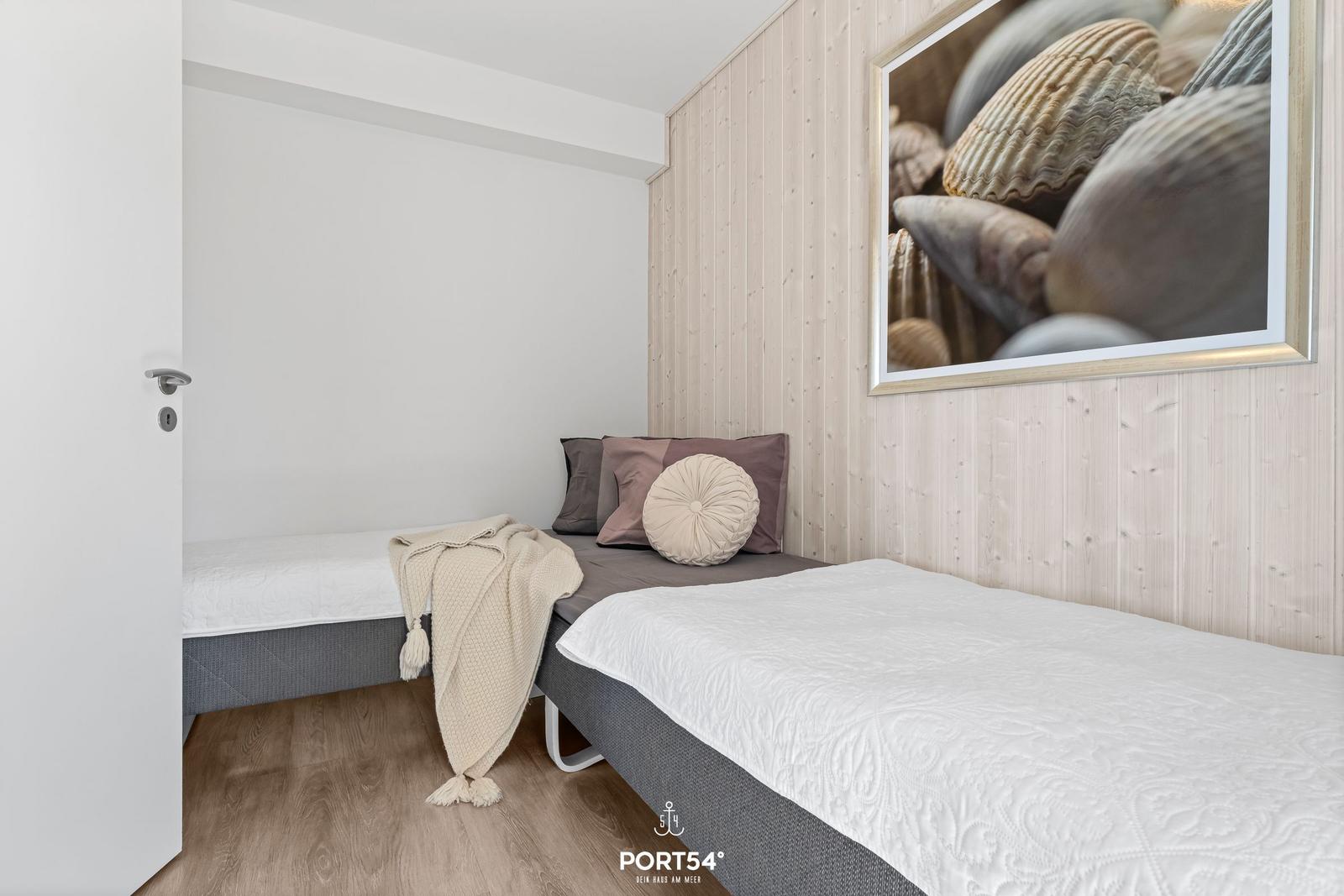 Zimmer mit zwei Betten, Holzwand und Meeresmuschel-Bild an der Wand.