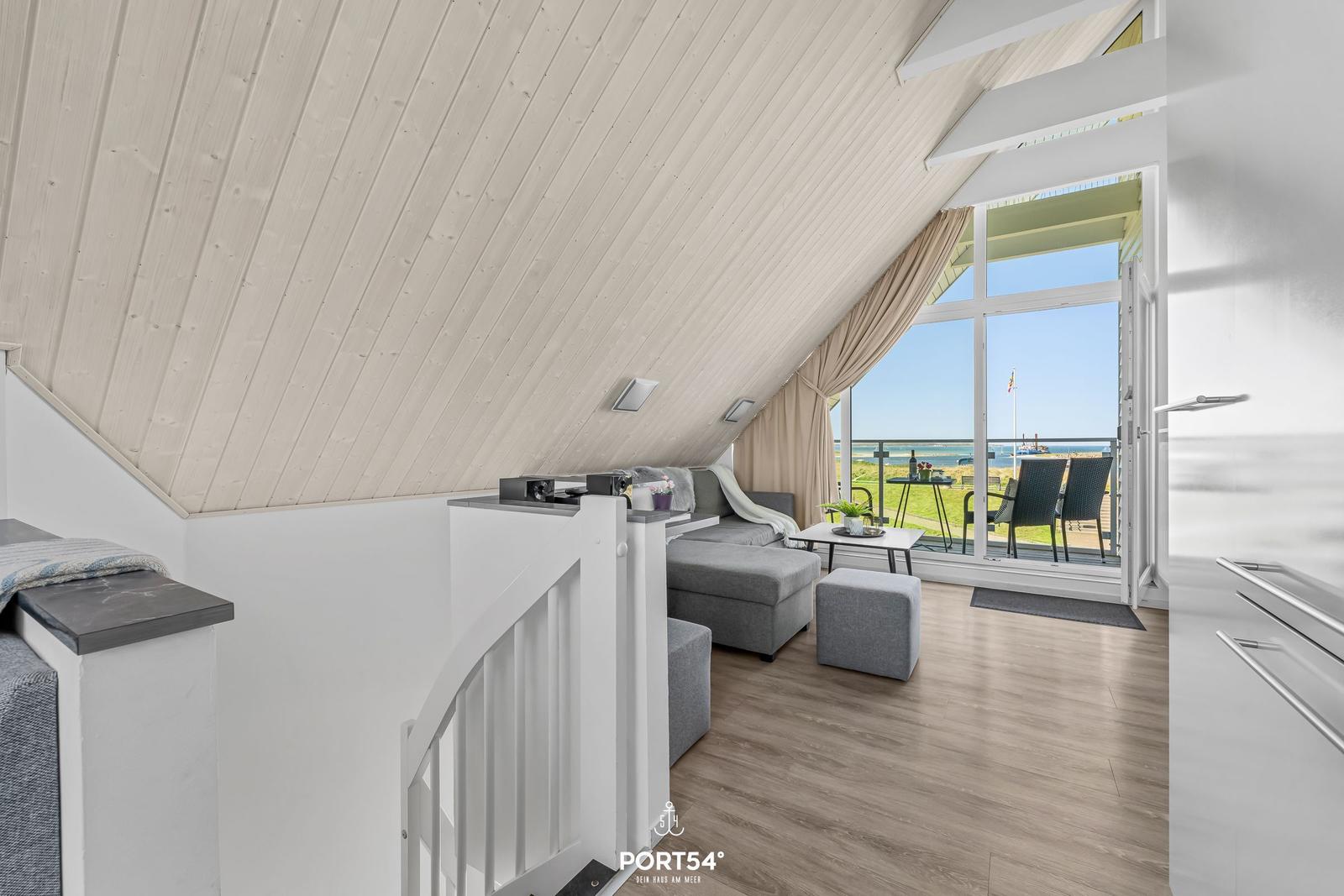 Wohnbereich mit Blick auf den Strand und Terrasse mit Sitzgelegenheiten.