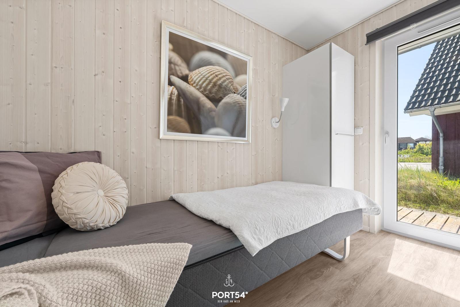 Schlafzimmer mit Bett, Wandbild und Tür zum Außenbereich.