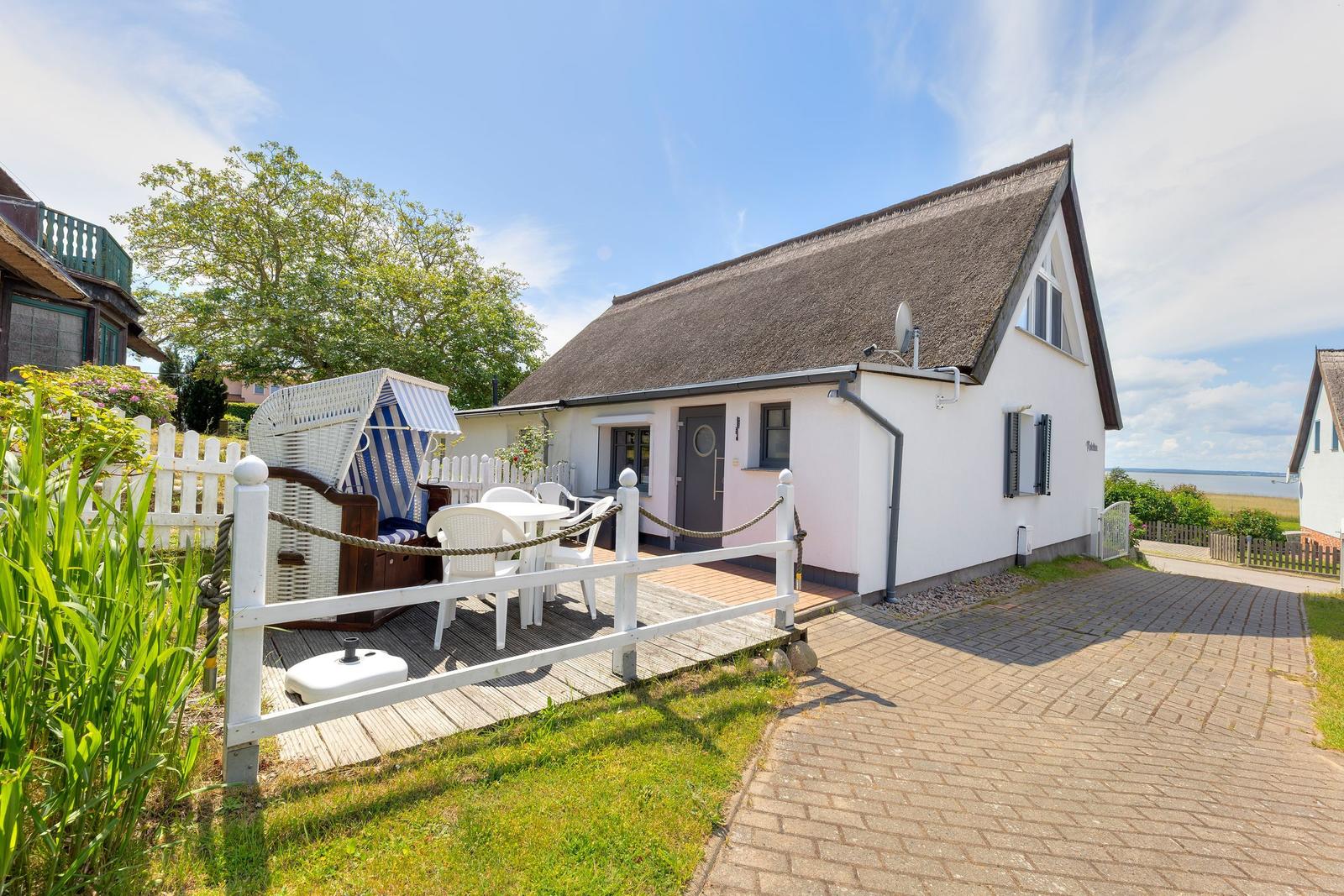 Wohnhaus mit Dachterrasse, weiße Umzäunung und Strandkorb im Vorgarten.