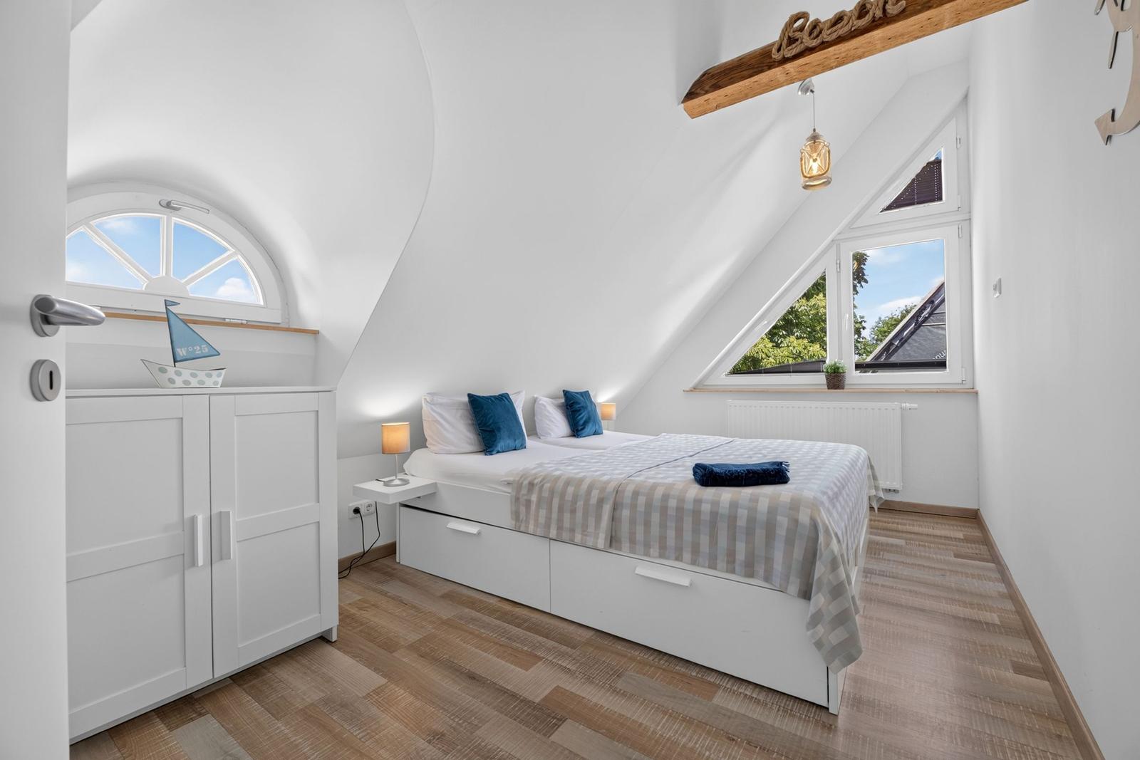 Schlafzimmer mit Dachschräge, Bett, Schrank und Fenster
