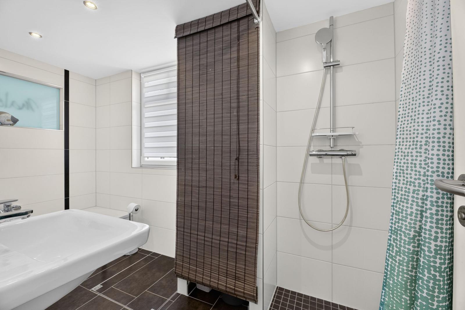 Badezimmer mit Dusche, Badewanne und Fenster