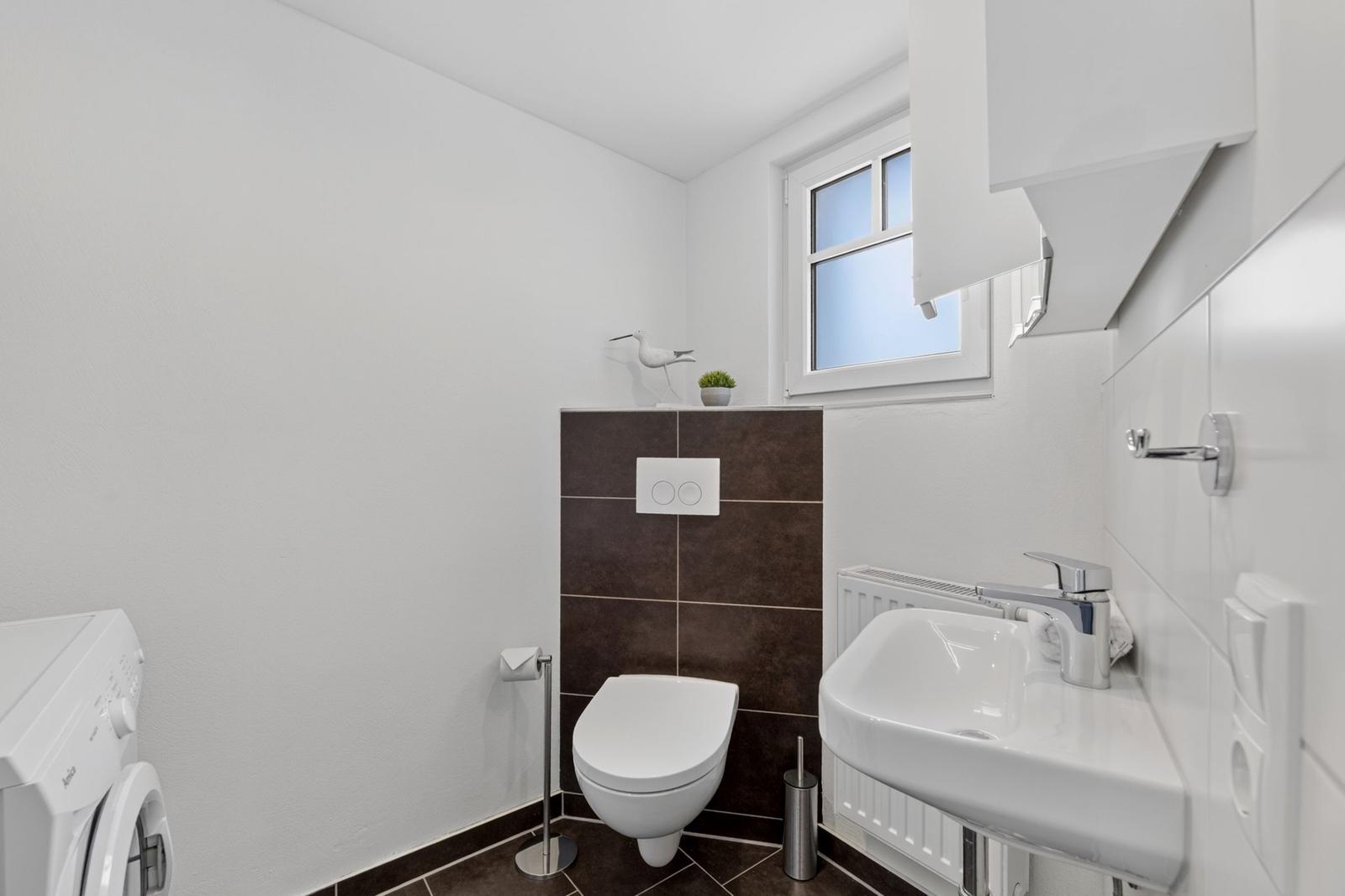 Badezimmer mit Toilette, Waschbecken und Fenster