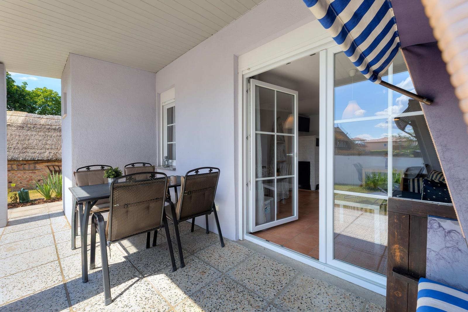 Terrasse mit Tisch, Stühlen und Schiebetür zum Innenraum.