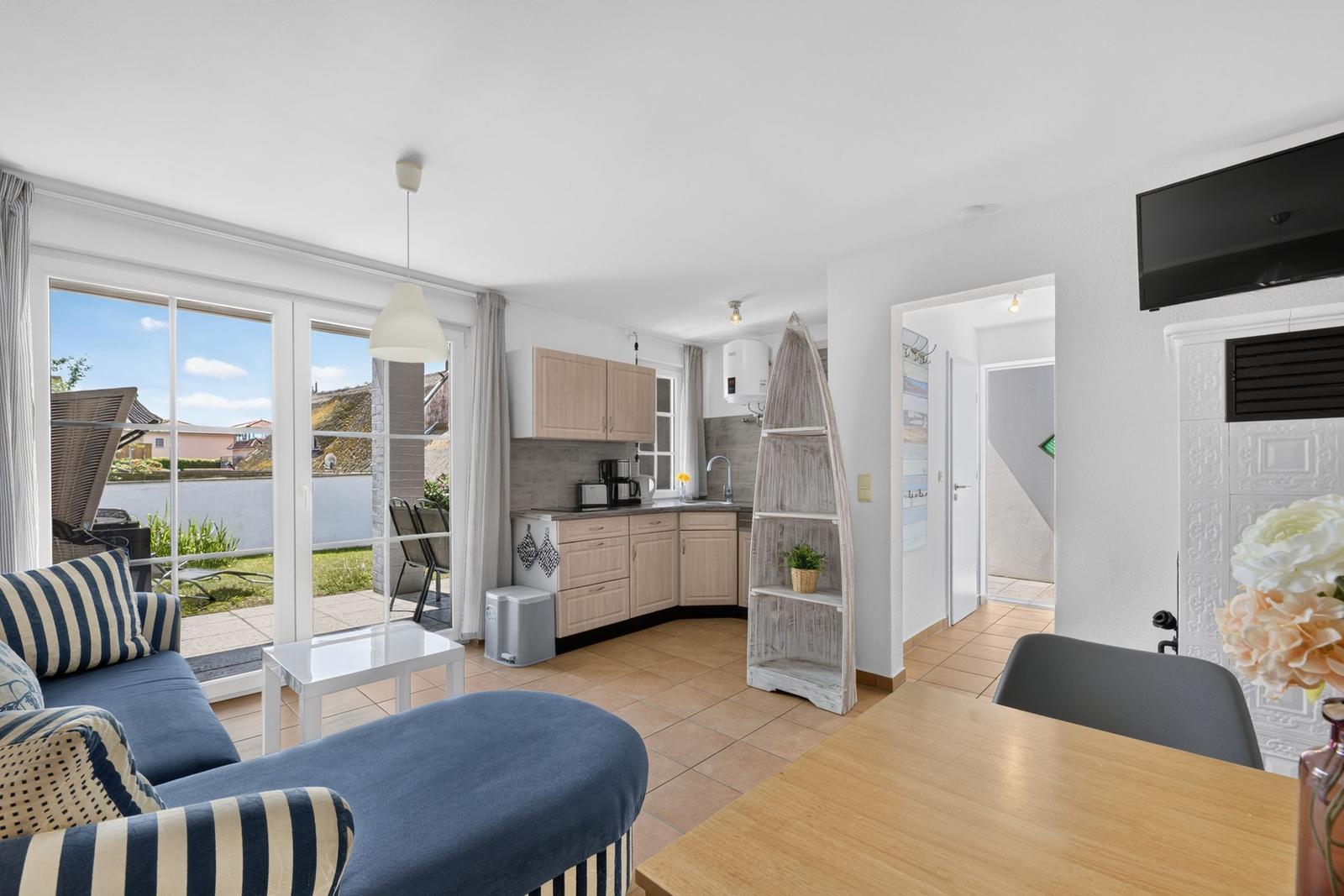 Wohnbereich mit Küche, Schlafzimmer und Terrasse. Modern eingerichtet mit Sofa und Esstisch.