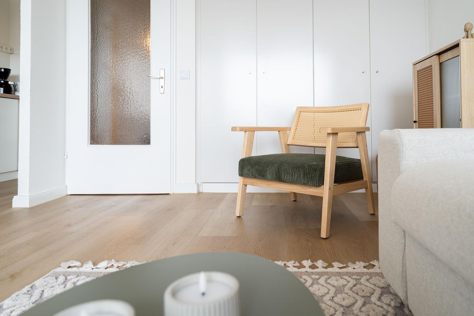 A chair with a green seat and wooden frame is in the living room.